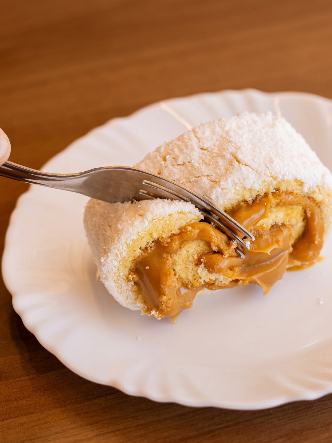 Fatia de bolo de rolo com doce de leite e coco no prato