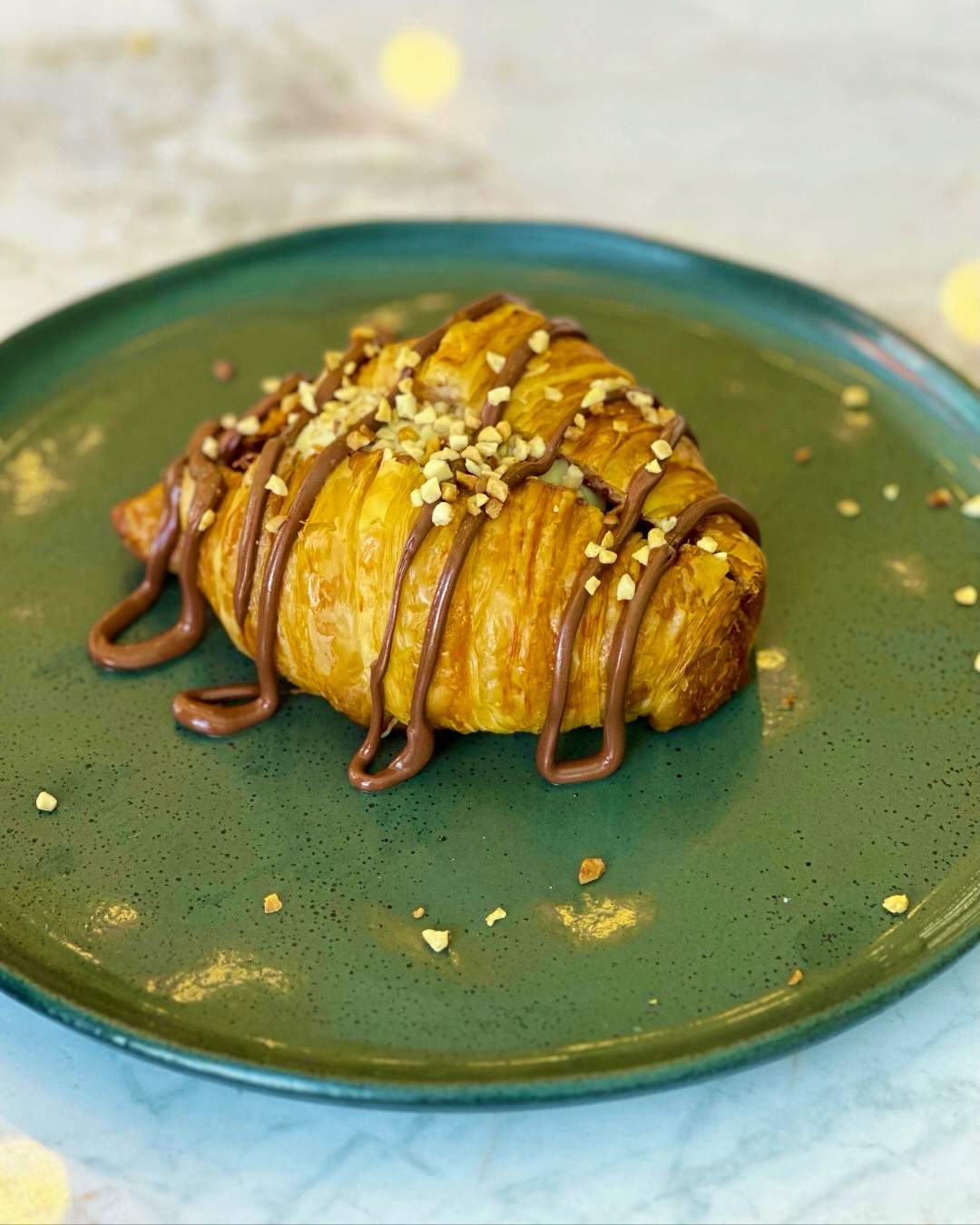 Croissant com calda de chocolate e castanhas picadas